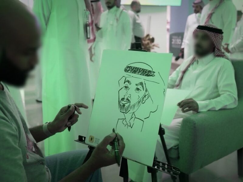 فنان يرسم كاريكاتير لأحد الحضور خلال فعالية