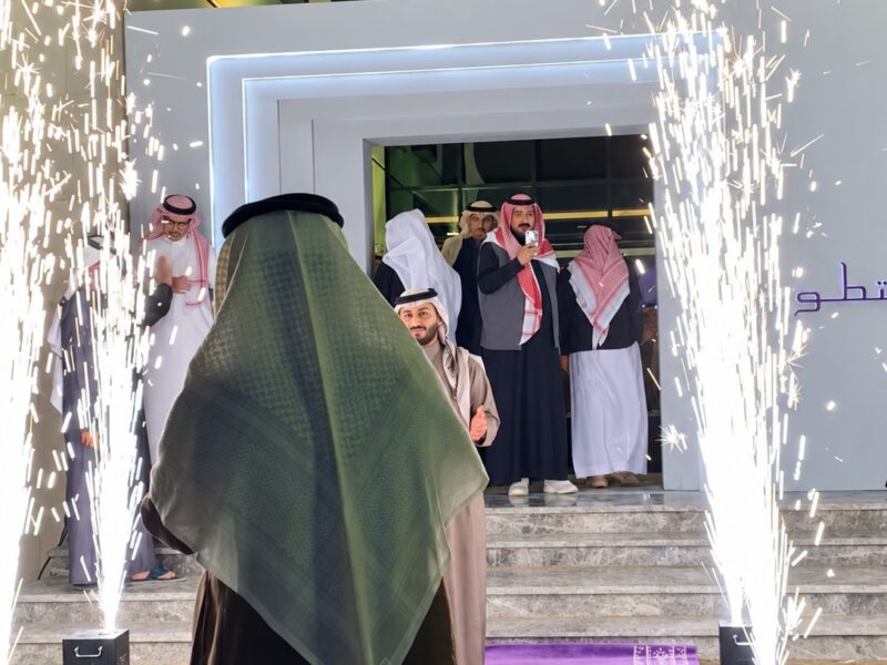 استقبال الحضور عند مدخل الفعالية مع عروض الشرر والهوية الظاهرة على المدخل